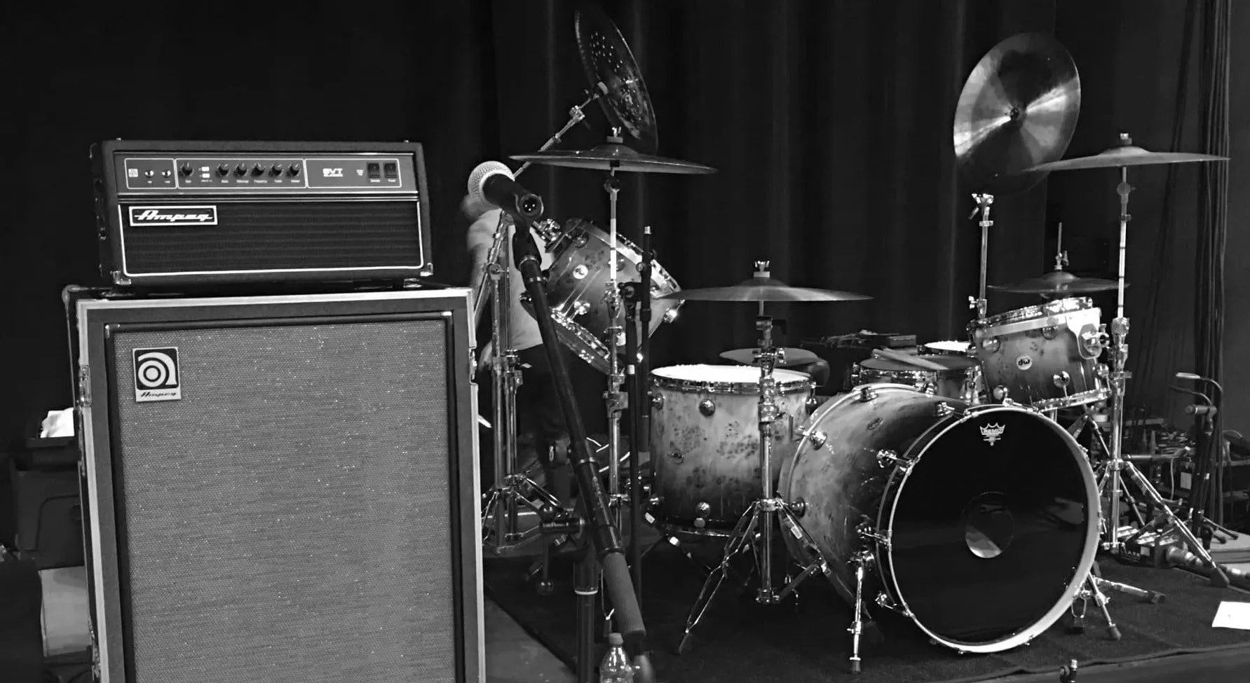 A drum kit and Ampeg amplifier stack set up on stage